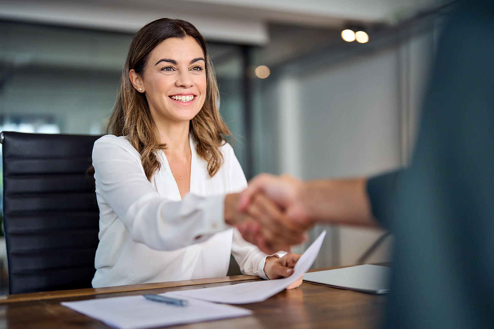 HR-professional schudt een nieuwe opdrachtgever de hand aan een vergadertafel